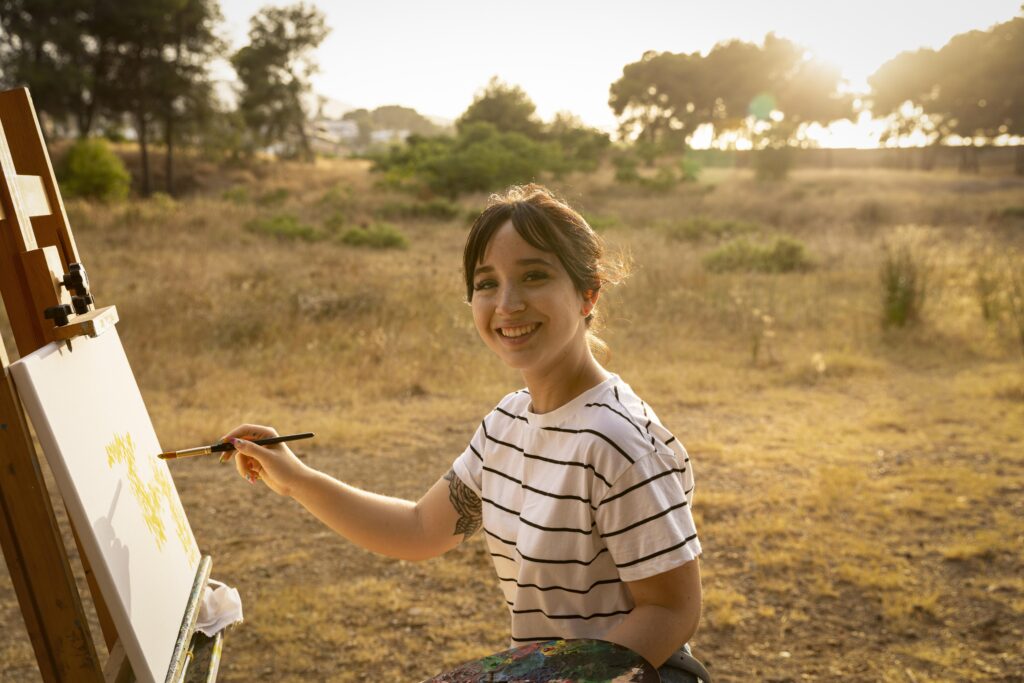woman painting canvas outside nature